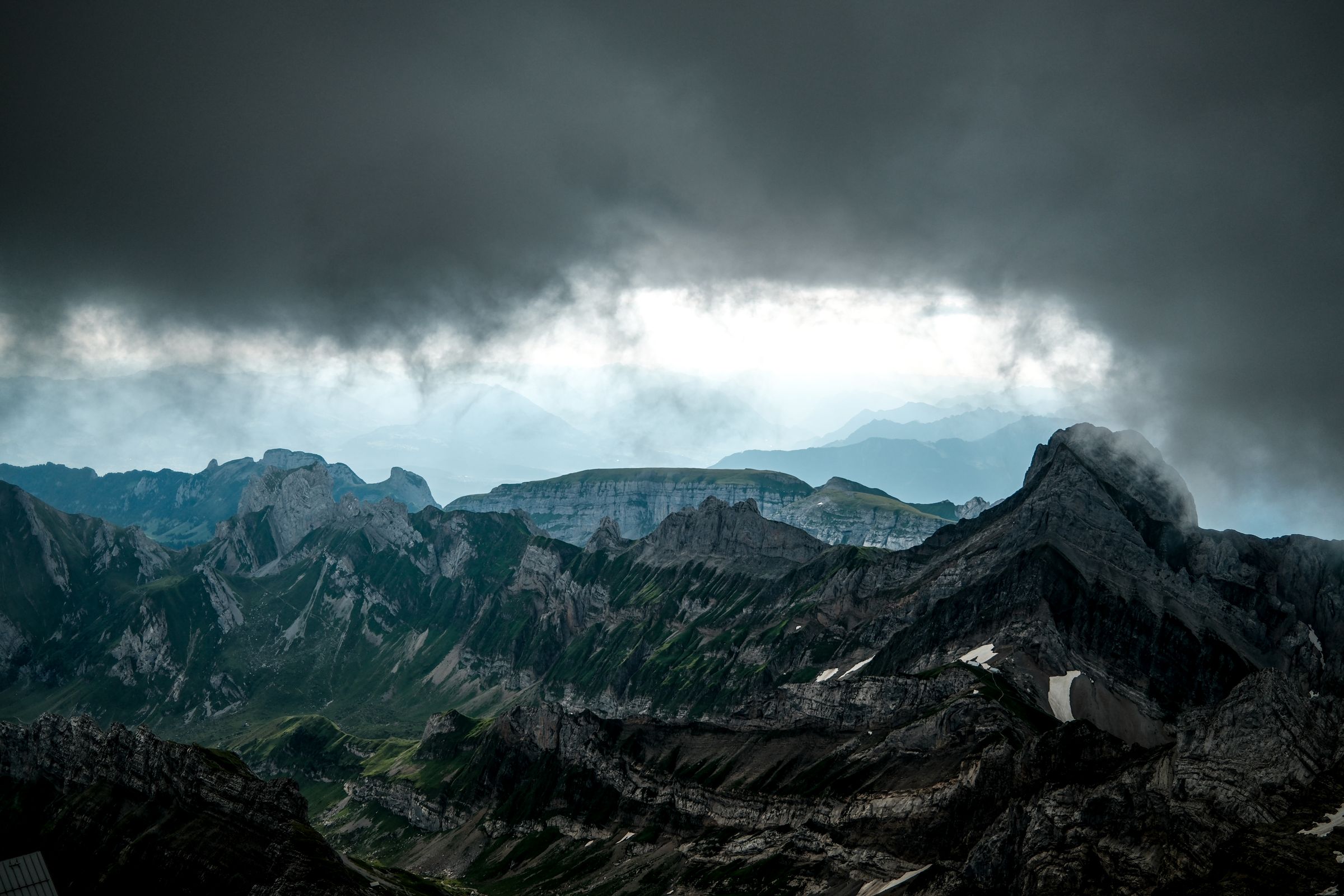 Dunkle Wolkendecke über schroffen Kalkgipfeln, dahinter Licht