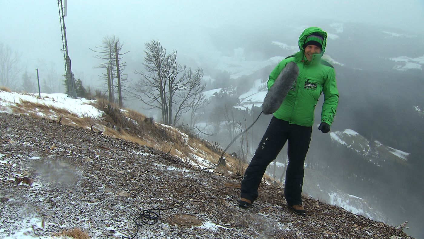 Sebastian Weber mit Mikrofon im Sturm auf einem Berggipfel