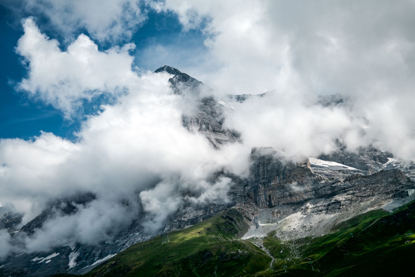 Wolken reißen um eine steile Felswand auf